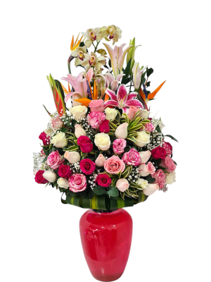 Arreglo floral en florero rojo con rosas, lirios y orquídeas en tonos rosados y blancos.