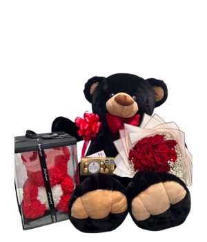 Oso de peluche negro con flores rojas y un osito de flores.