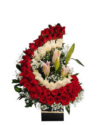 Arreglo floral en media luna con rosas rojas y blancas, lirios y follaje perla, ideal para ocasiones románticas o elegantes.