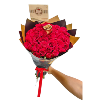 Buchón de rosas rojas con una rosa dorada, papel coreano y cinta roja, ideal para detalles elegantes.