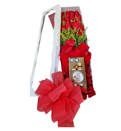 Caja blanca con 12 rosas rojas, follaje, pétalos, chocolates Ferrero y moño, un detalle elegante y romántico.