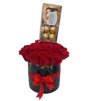 Caja negra con rosas rojas frescas y chocolates Ferrero Rocher, decorada con lazo rojo.