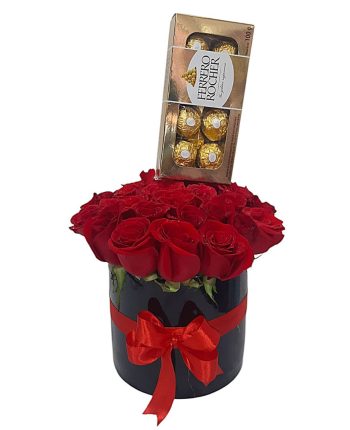 Caja negra con rosas rojas frescas y chocolates Ferrero Rocher, decorada con lazo rojo.