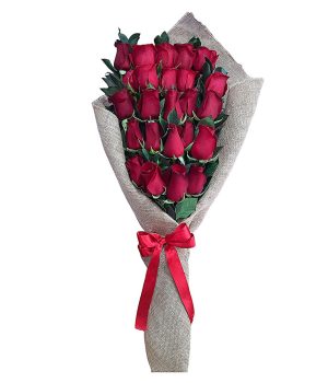 Ramo elegante de rosas rojas frescas envuelto en tela rústica con lazo rojo.