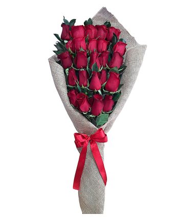 Ramo elegante de rosas rojas frescas envuelto en tela rústica con lazo rojo.